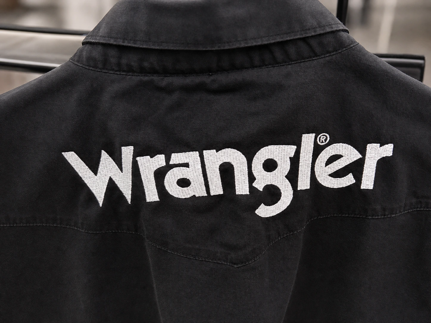 Close view of white Wrangler embroidery stitches on black fabric