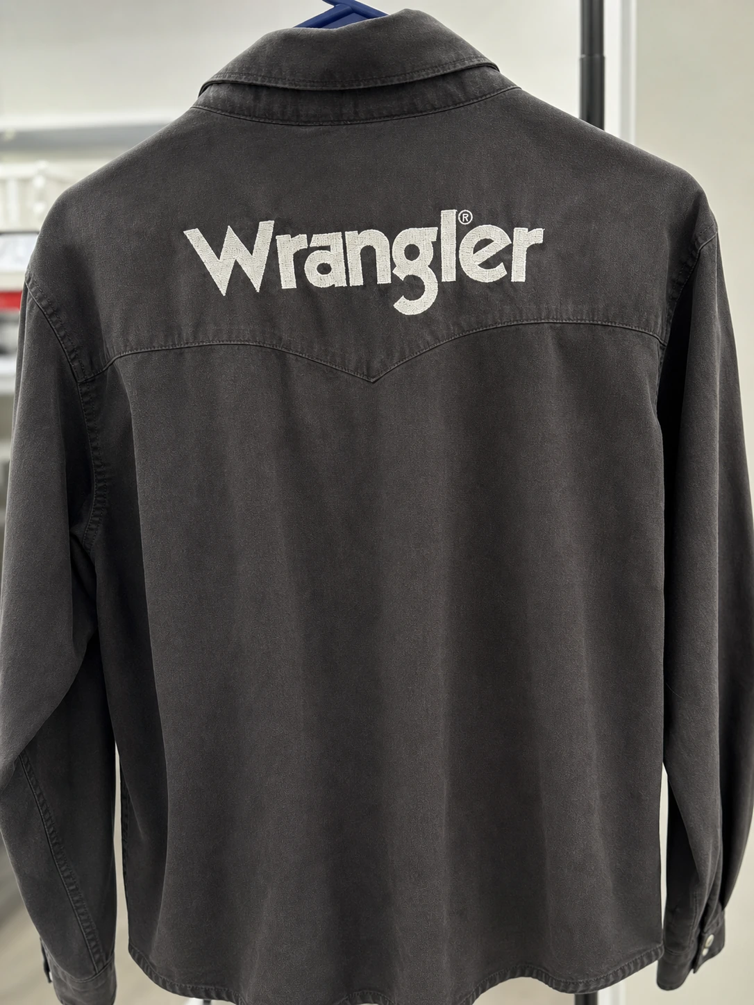 Back of black western shirt with large white Wrangler embroidery across the yoke