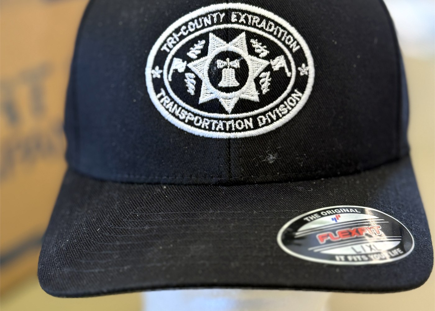 White Tri-County Extradition embroidery on a black Flexfit hat